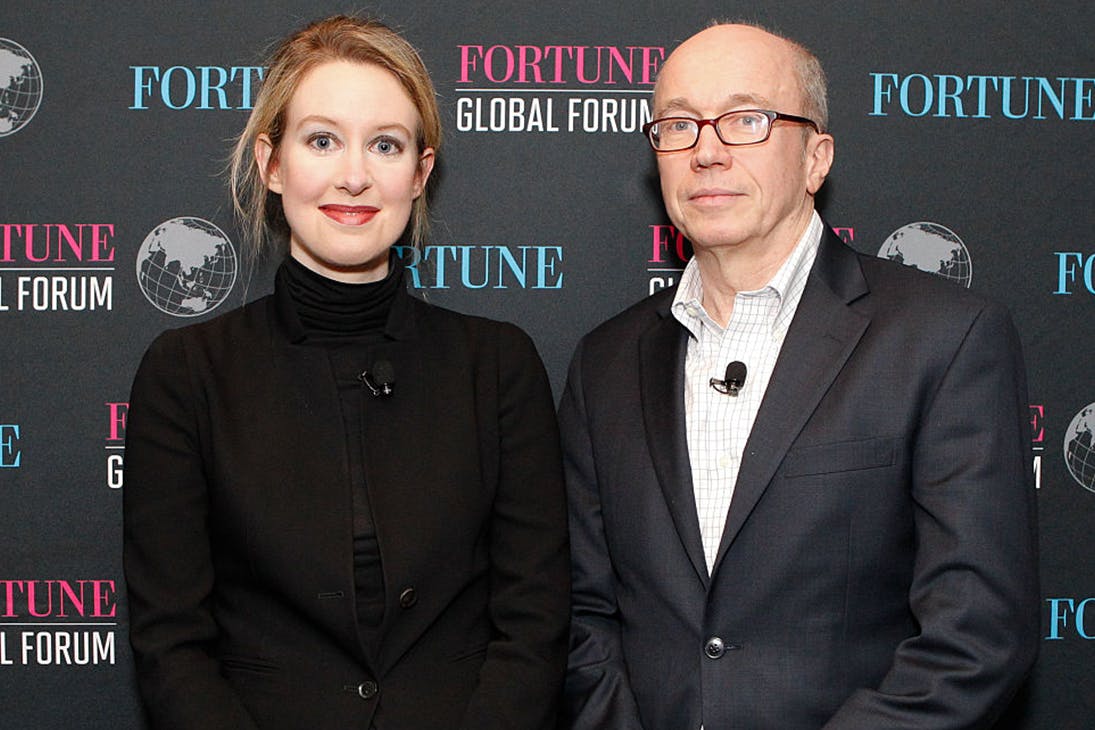 Elizabeth Holmes poses in front of a media wall